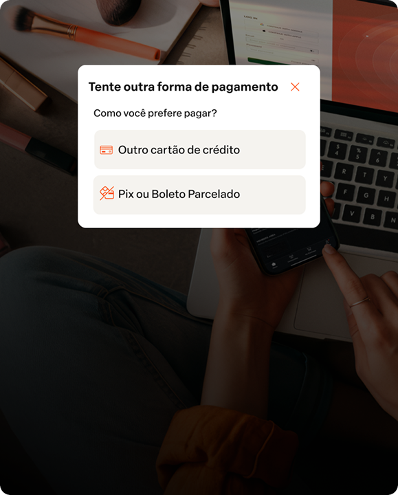 Tela de um celular apresentando opções de pagamento, como cartão de crédito, cartão pela internet e boleto parcelado, com uma pessoa usando o telefone na mesa de madeira.